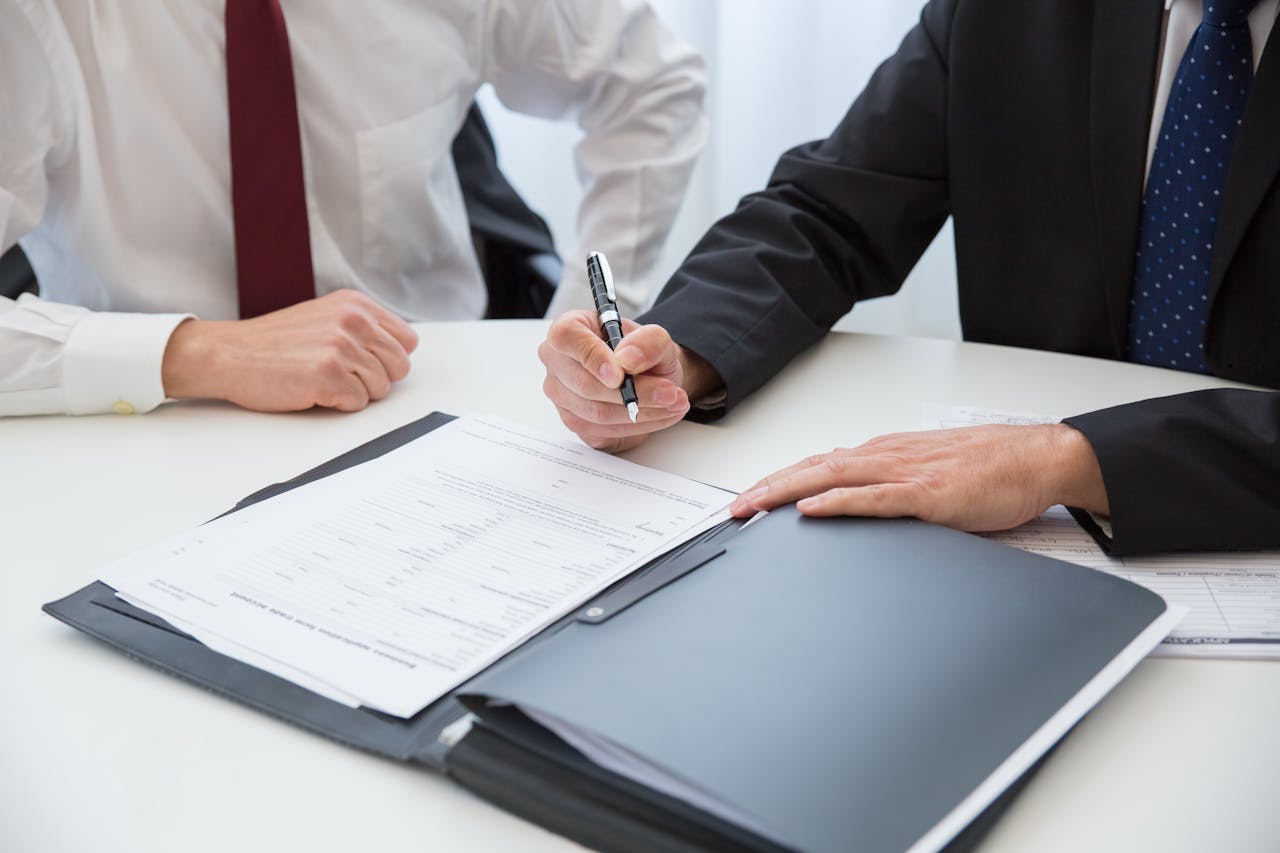 Two professionals signing a contract at a business meeting in an office.