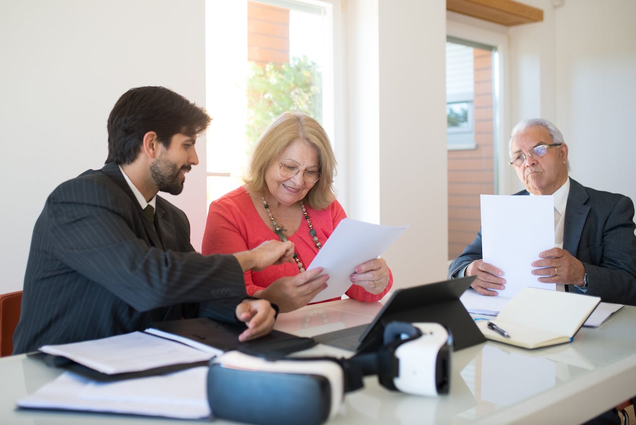 Three professionals collaborate during a business meeting, reviewing documents in a modern office setting.